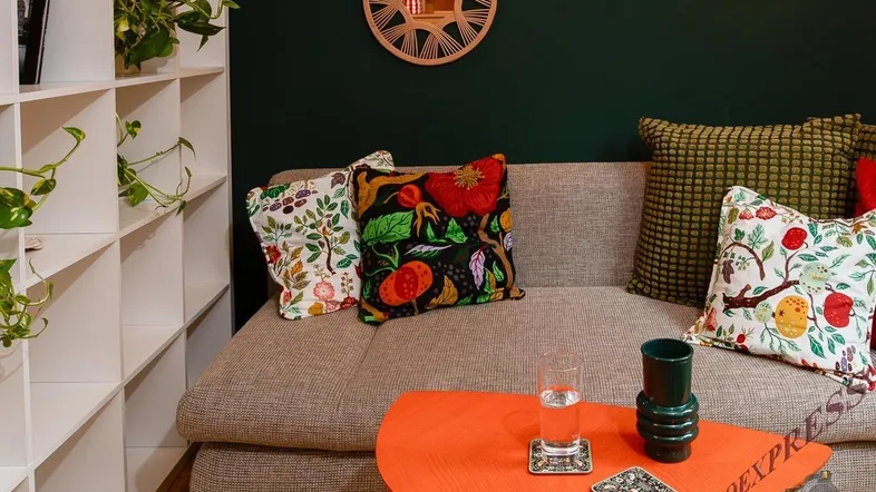 Gemütliches Wohnzimmer mit dunkler Wandfarbe, bequemer Couch und dekorativen Kissen.