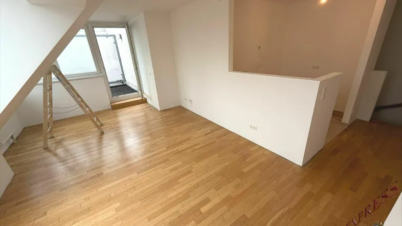 Heller Raum mit Holzboden, Dachschrägen und Zugang zu einem Balkon, bereit zur individuellen Gestaltung.