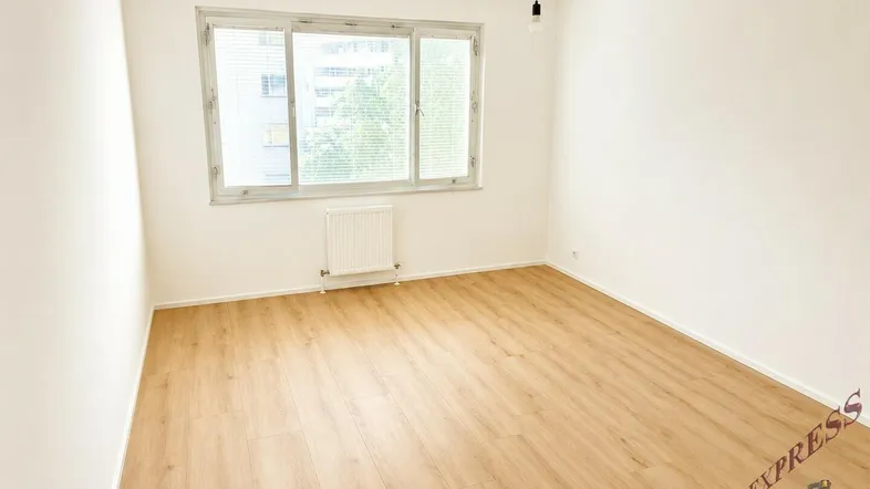 Helles, leeres Zimmer mit Laminatboden und großem Fenster, ideal als Schlafzimmer oder Büro.