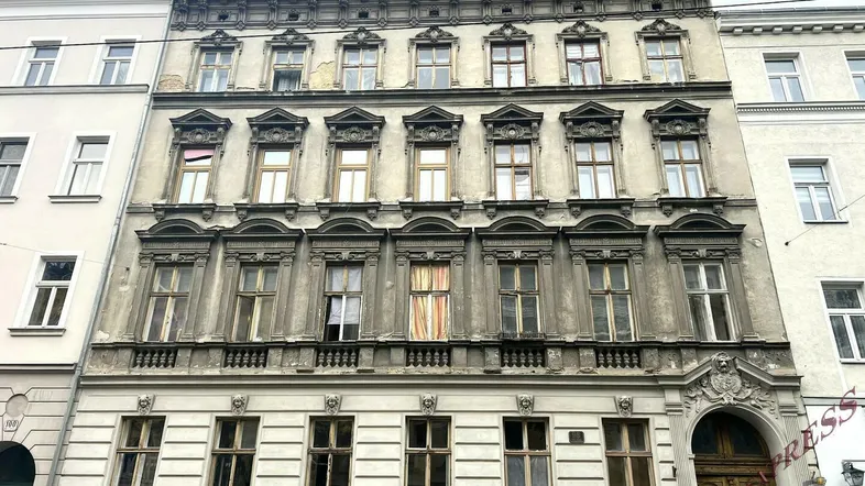 Altes Gebäude mit reich verzierter Fassade und vielen Fenstern, zeigt klassischen Baustil und historische Details.