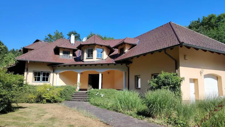 Großzügiges Einfamilienhaus mit weitläufigem Vorgarten und einladendem Eingangsbereich unter einem Vordach.