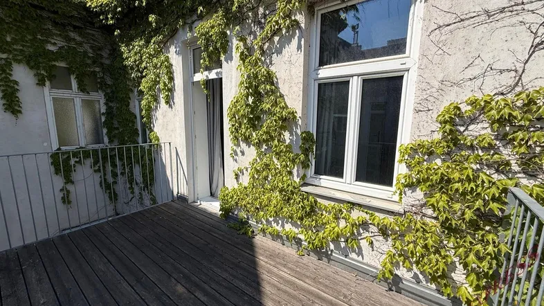 Geräumiger Balkon mit Holzboden und begrünten Wänden, ideal für entspannte Stunden im Freien.