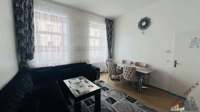 Geräumiger Wohn-Essbereich mit dunklem Ecksofa, Esstisch und großen Fenstern.