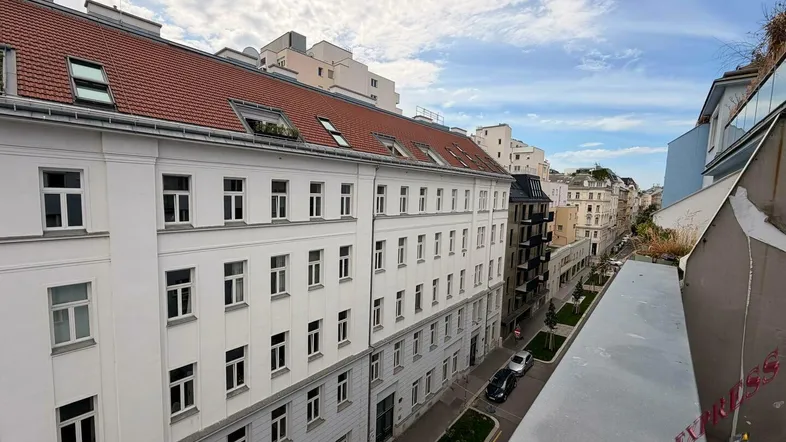 Blick von oben auf eine belebte Stadtstraße mit historischen Gebäuden und rotem Dach.