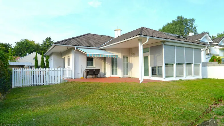 Großer Gartenbereich hinter dem Haus mit Rasenfläche, Terrasse und Markise für Schatten.