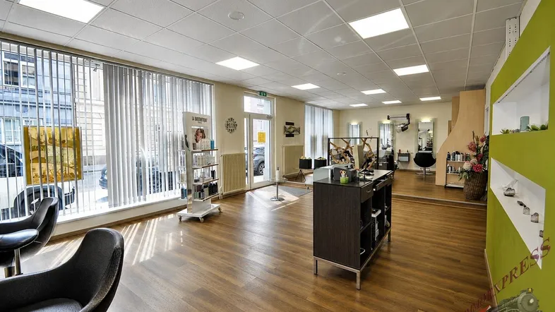 Heller und geräumiger Friseursalon mit großen Fenstern, Holzfußboden und modernen Arbeitsplätzen.