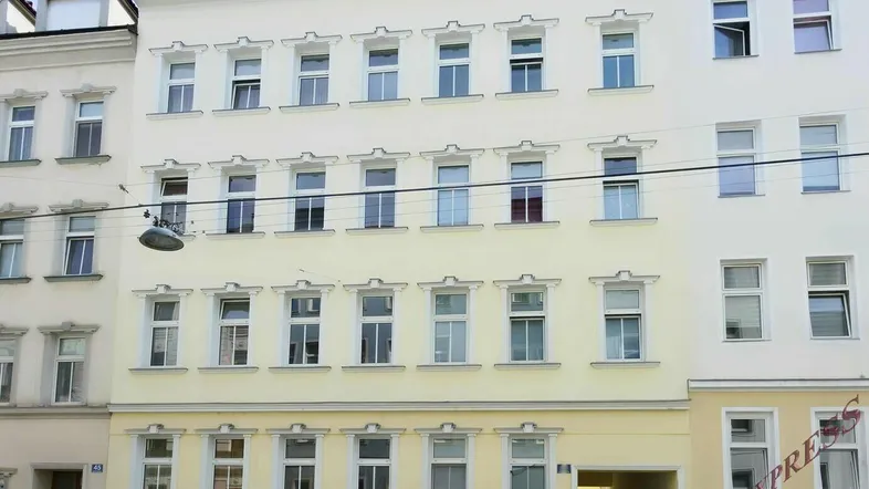 Mehrstöckiges Wohngebäude mit klassischer Fassade und vielen Fenstern in einer städtischen Umgebung.