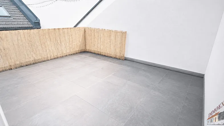 Geräumige Dachterrasse mit Fliesenboden und Bambus-Sichtschutz, ideal für Entspannung im Freien.