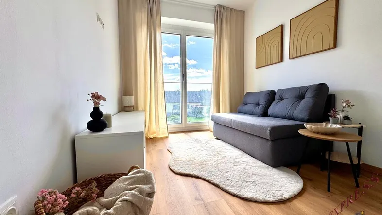 Helles Wohnzimmer mit beigem Sofa, Holzboden und Zugang zu einem Außenbereich.