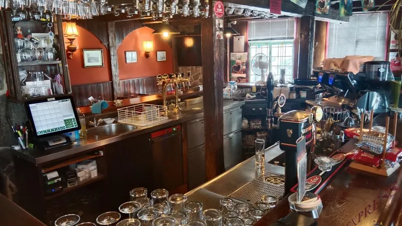 Traditionelle Bar mit Zapfanlage, vielen Gläsern und einem Kassensystem, bereit für den Betrieb.