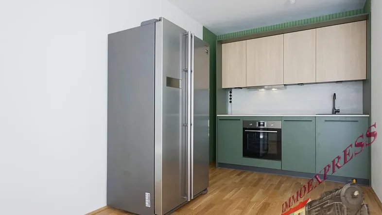 Moderne Küche mit grünen Unterschränken, hellen Holzfronten und integriertem Backofen.