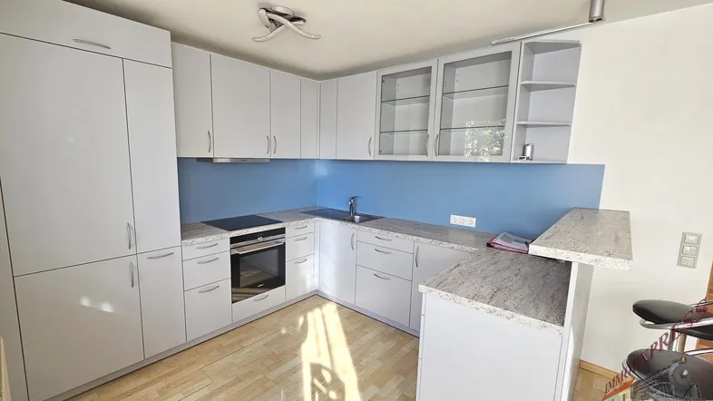 Moderne Küche mit hellgrauen Schränken, blauer Rückwand, Holzboden und einer Frühstückstheke.
