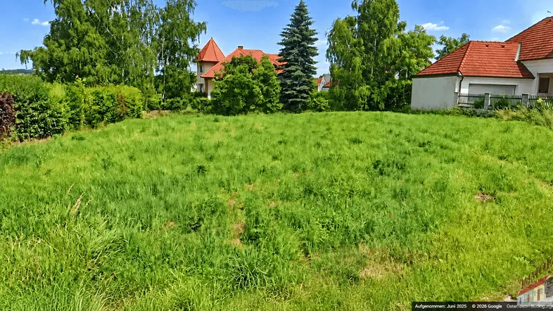 Weitläufiges Grundstück mit grüner Wiese, umgeben von Bäumen und Wohnhäusern in ländlicher Umgebung.