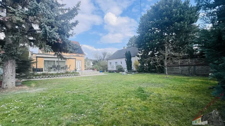 Großer, gepflegter Garten mit Rasenfläche und Blick auf das Haus sowie eine Terrasse.
