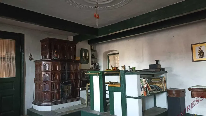 Traditionelles Wohnzimmer mit Kachelofen, Holzbalken und Stuckdecke, eingerichtet im rustikalen Stil.