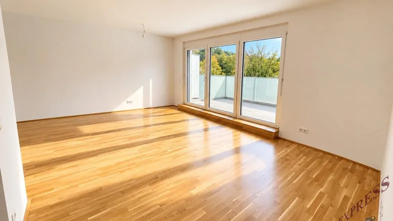 Helles Wohnzimmer mit Parkettboden, großen Fenstern und Zugang zu einer Terrasse.