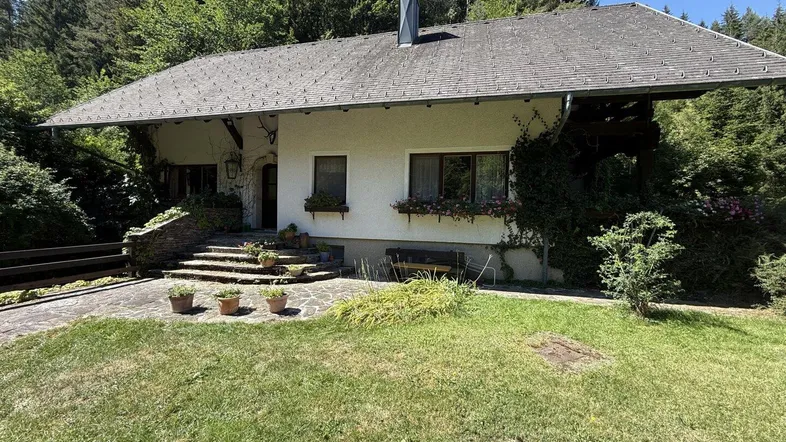 Traditionelles Haus mit Satteldach und großem Garten, umgeben von Wald und Natur.