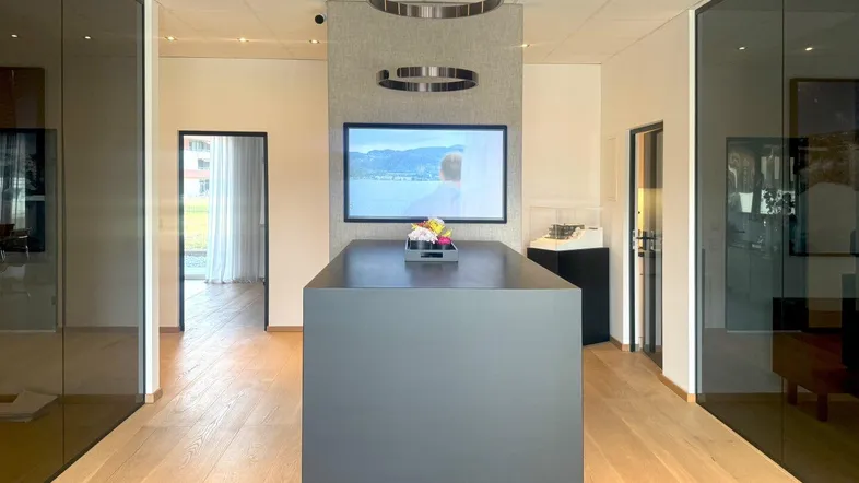 Moderner Empfangsbereich oder offener Büroraum mit Holzboden, dunklen Glaswänden und stilvoller Beleuchtung.