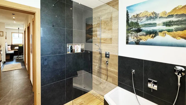 Modernes Badezimmer mit begehbarer Dusche, Eckbadewanne und dunklen Fliesen.