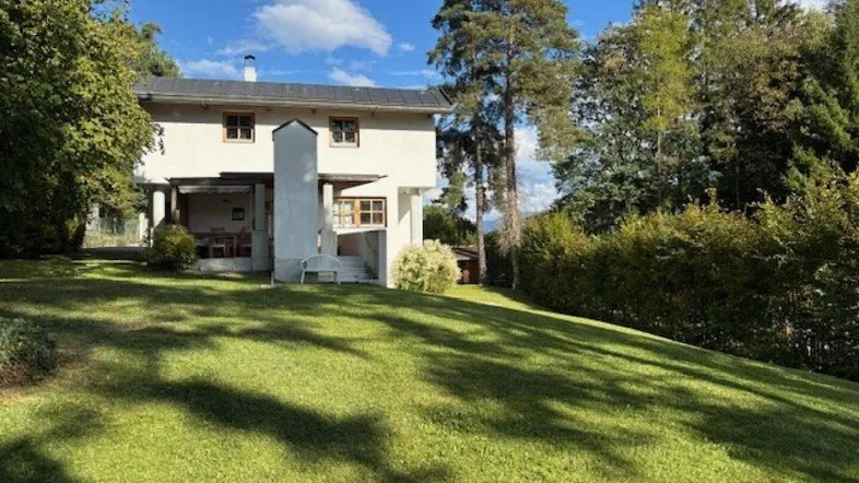 Weißes Haus mit großem grünen Garten und weitem Blick auf die umliegende Berglandschaft.