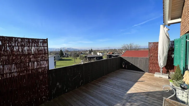Geräumige Holzterrasse mit Weitblick über die Landschaft und die umliegenden Berge.