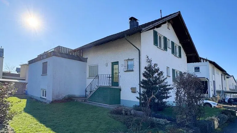 Vorderansicht des Hauses mit gepflegtem Vorgarten und sonnigem Rasenbereich.