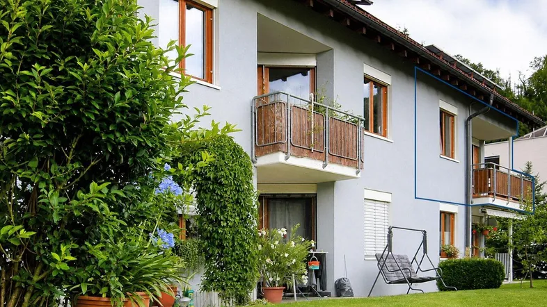 Mehrfamilienhaus mit gepflegtem Gartenbereich, Balkonen und einer Schaukel im Grünen.