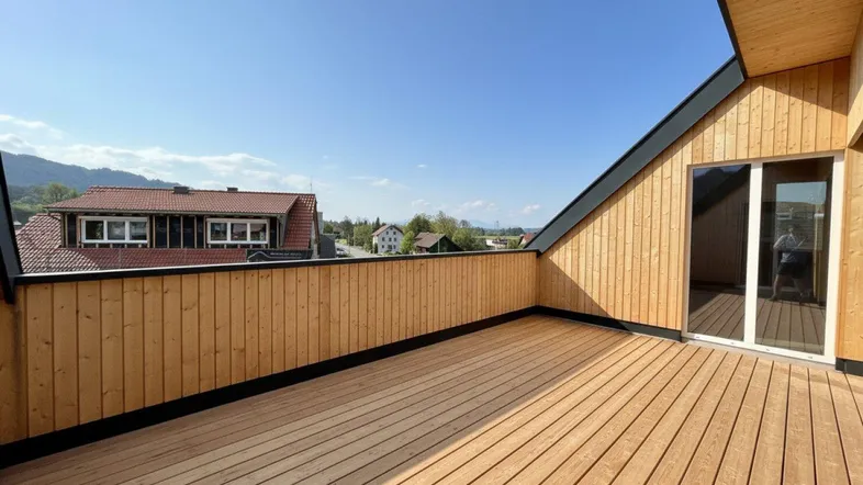 Geräumige Holzterrasse mit weitem Blick über die Umgebung und angrenzende Häuser.