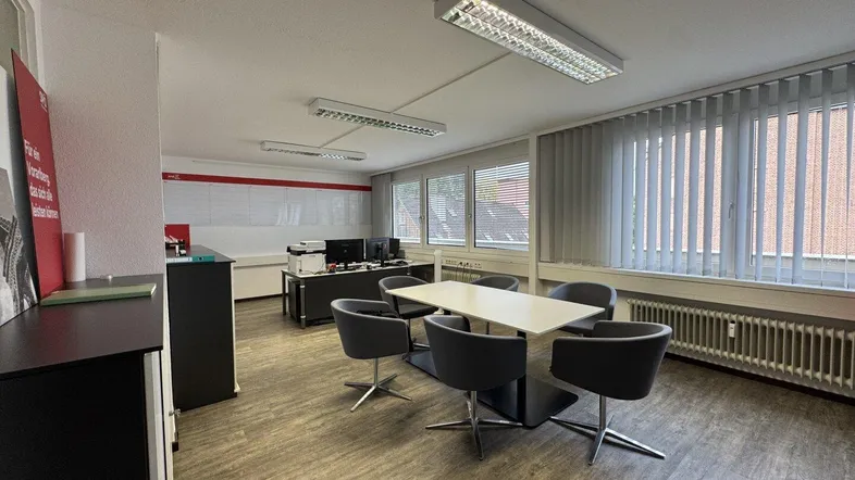 Geräumiges Büro mit modernem Laminatboden, großen Fenstern und einem Konferenztisch für Besprechungen.