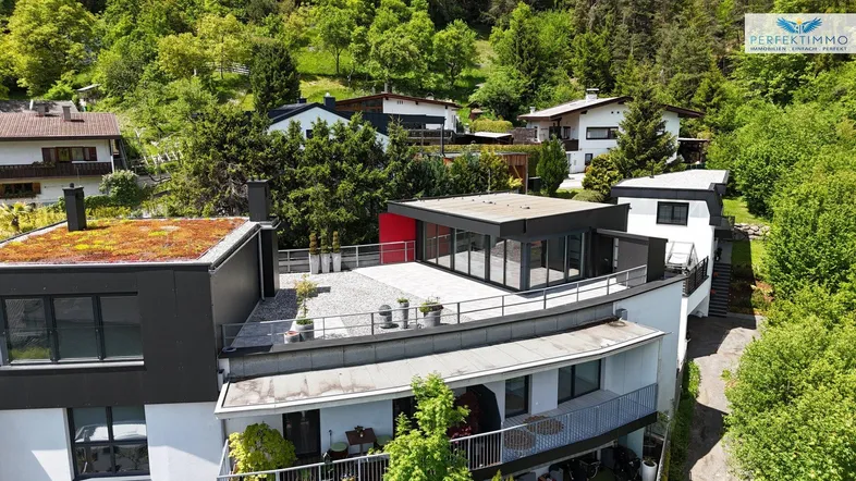 Moderne Wohnanlage mit begrüntem Flachdach und großzügiger Dachterrasse in grüner Umgebung.