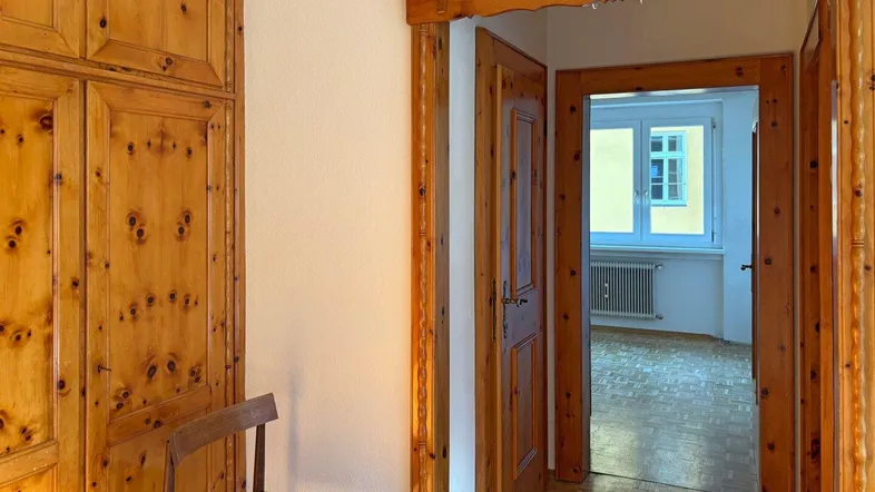 Eingangsbereich mit rustikalen Holzschränken und Blick in ein weiteres Zimmer mit Parkettboden.