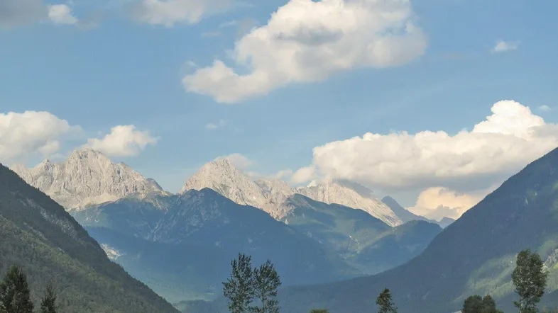 Malerische Berglandschaft mit weiten Tälern und grünen Wiesen unter blauem Himmel.