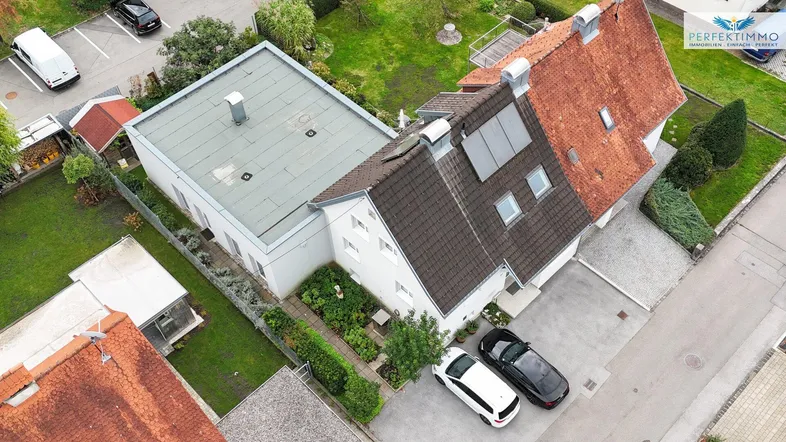 Luftaufnahme des Anwesens mit mehreren Gebäuden, Gärten und Parkplätzen in einer Wohngegend.