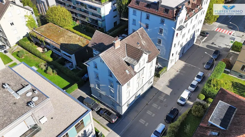 Luftaufnahme eines Wohngebäudes mit Satteldach und umliegenden Straßen und Häusern.