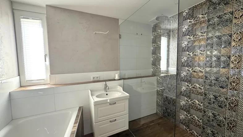 Modernes Badezimmer mit Badewanne, begehbarer Dusche und dekorativen Fliesen an der Wand.