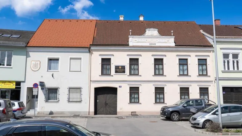 Historisches Gebäude mit klassischer Fassade und Satteldach an einer Straße.