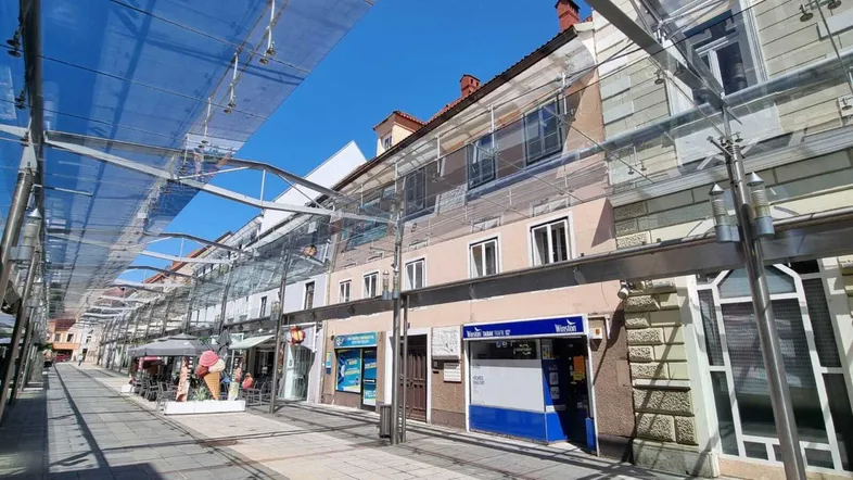 Blick auf eine belebte Einkaufsstraße mit historischen Gebäuden und einer modernen Glasüberdachung.