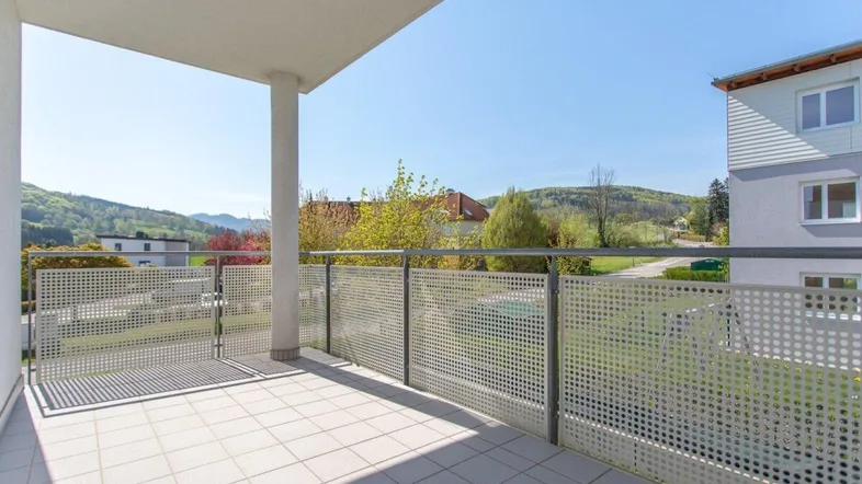 Geräumiger Balkon mit Fliesenboden und weitem Blick auf die umliegende Hügellandschaft.