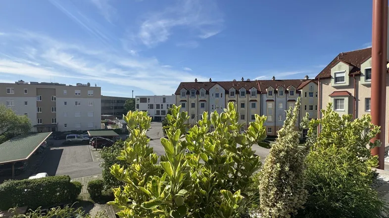 Blick von einem Balkon auf die umliegenden Wohngebäude und den Parkplatz der Anlage.