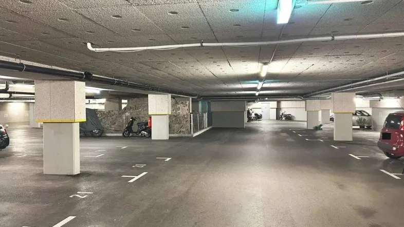 Geräumige Tiefgarage mit zahlreichen Stellplätzen und Betonpfeilern, gut beleuchtet und sauber.