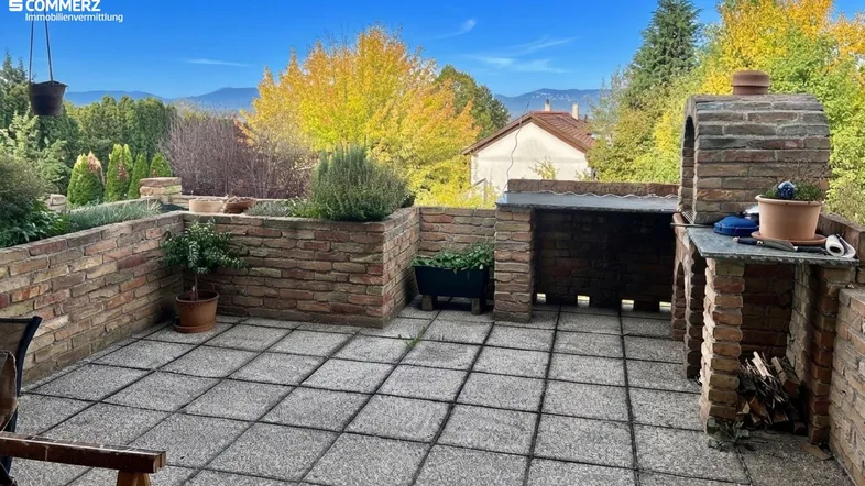 Geräumige Terrasse mit gemauertem Grillbereich, ideal für Mahlzeiten im Freien und Entspannung.