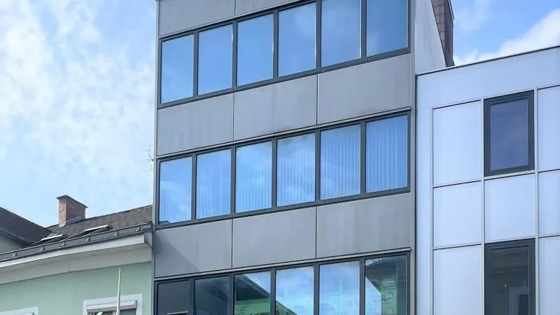 Modernes Gebäude mit großer Glasfassade und klaren Linien in städtischer Umgebung.