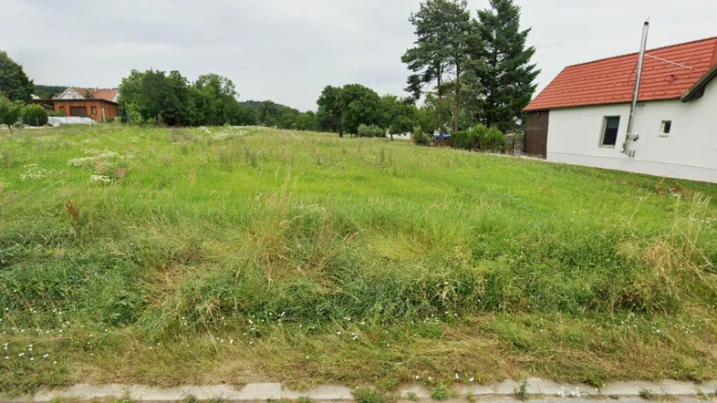 Weitläufiges grünes Grundstück mit einem Haus im Hintergrund, umgeben von Bäumen und ländlicher Natur.
