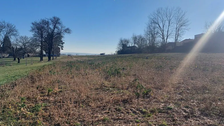 Weitläufiges Grundstück mit Blick auf die umliegende Landschaft unter einem klaren blauen Himmel an einem sonnigen Tag.