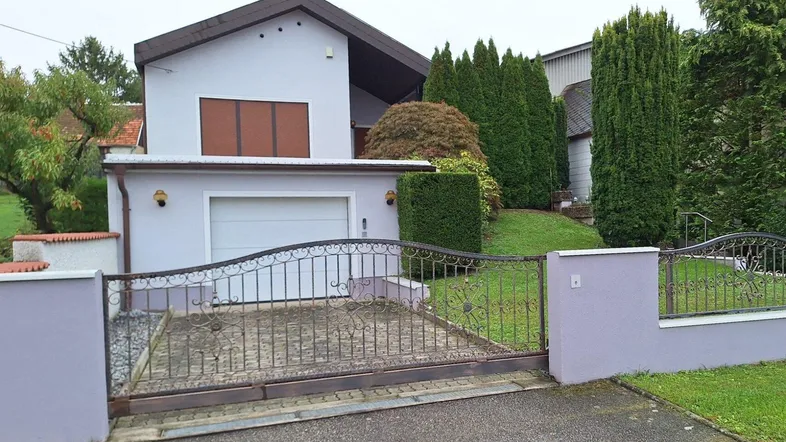 Einfamilienhaus mit Garage, gepflegtem Vorgarten und schmiedeeisernem Tor.