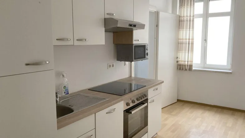 Helle Küche mit weißen Schränken, Holz-Arbeitsplatte und integrierten Geräten.