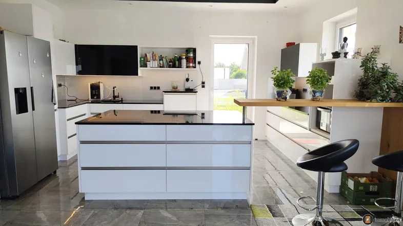 Moderne offene Küche mit weißer Kücheninsel, integrierten Geräten und Zugang zum Garten.