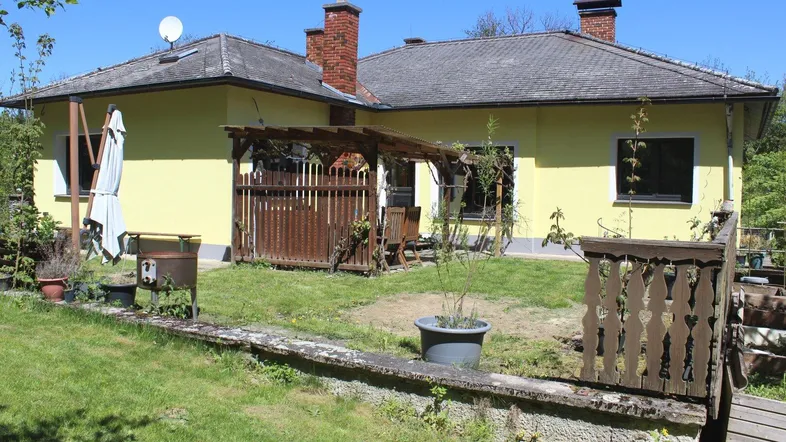 Hinterhof mit Rasenfläche, Holzpergola und Gartenmöbeln.