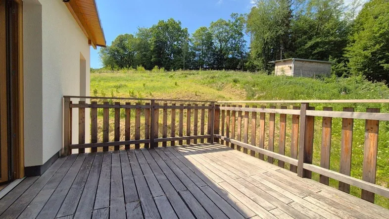 Geräumige Holzterrasse mit Blick ins Grüne und auf die umliegende Natur.