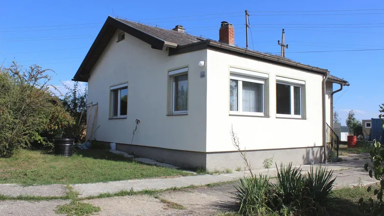 Einfamilienhaus mit Satteldach und weißer Fassade in ländlicher Umgebung.